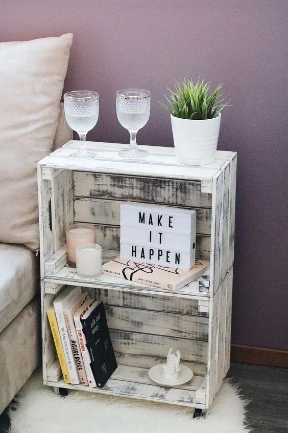 a shelf with some books and glasses on top of it next to a white couch