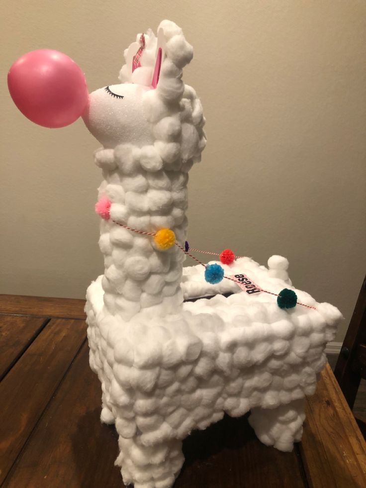 a sculpture of a llama with a balloon on it's head, sitting on top of a table