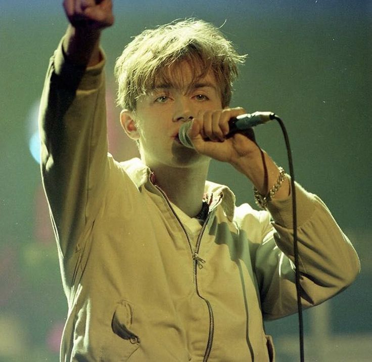 a young man holding a microphone up to the air while standing in front of a microphone