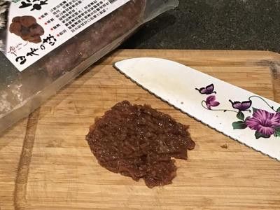 a knife sitting on top of a wooden cutting board next to a jar of food