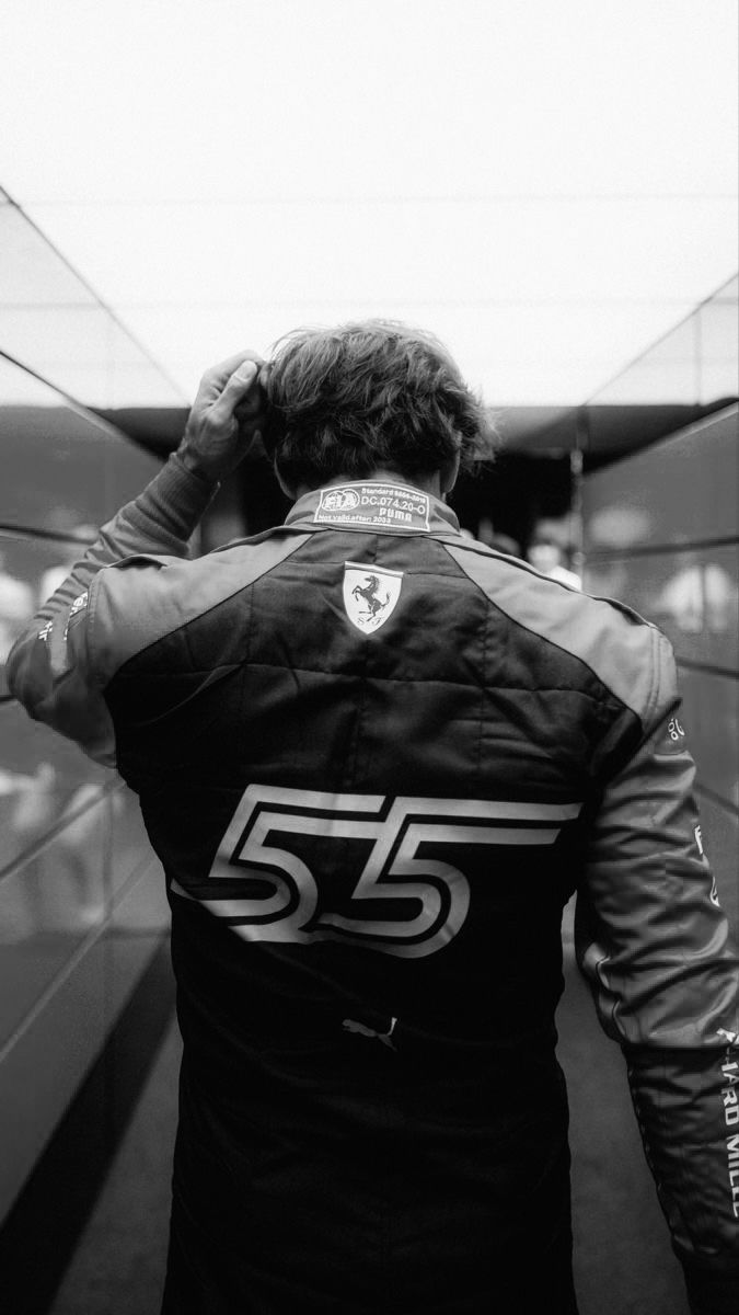 a man in a black and white racing suit is walking down the street with his hands on his head