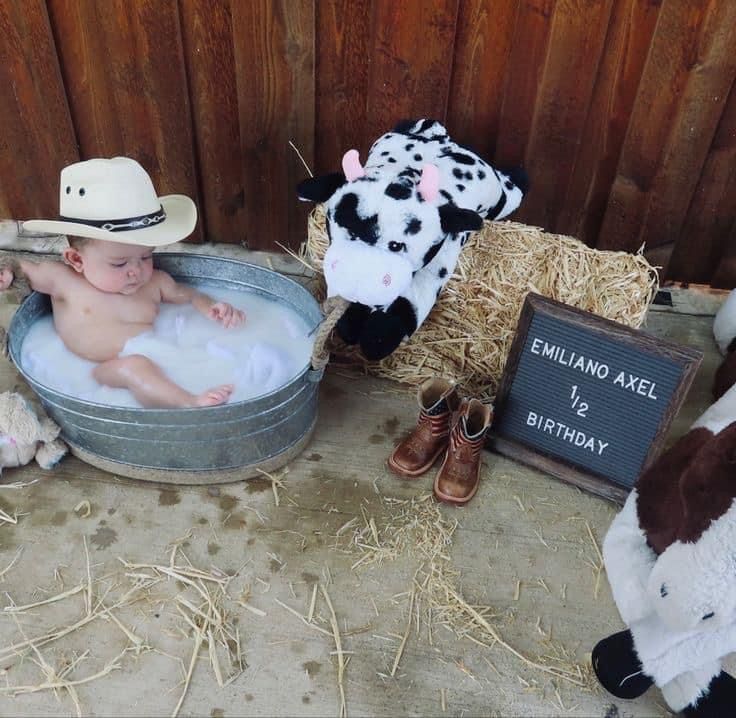 a baby sitting in a tub surrounded by stuffed animals and other items on the ground