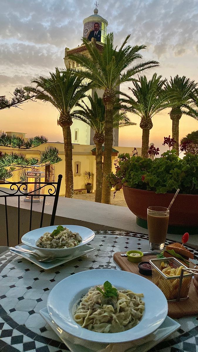 two plates of food sitting on top of a table next to a potted plant