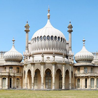 a large white building with many domes on it's sides and grass in the foreground