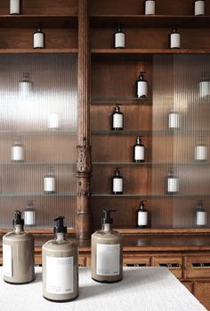 three bottles are sitting on a table in front of shelves with soap dispensers