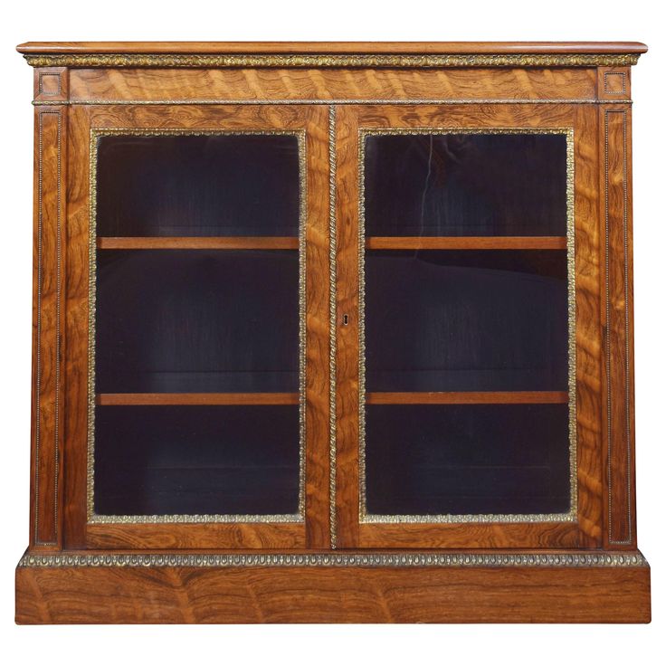 an old wooden bookcase with glass doors and gold trimmings on the sides