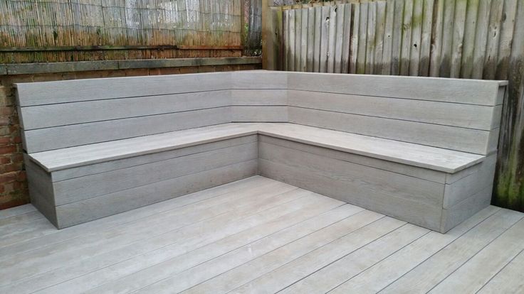 a corner bench sitting on top of a wooden deck