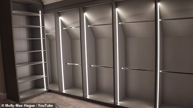 an empty walk - in closet with several shelves and lights on the doors, all lit up