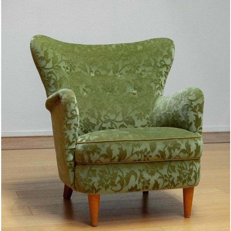 a green chair sitting on top of a hard wood floor next to a white wall