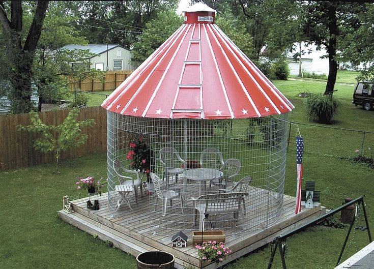 a large bird cage sitting on top of a wooden deck next to a picnic table