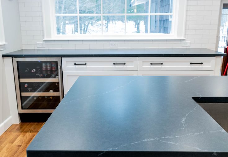 an empty kitchen with black counter tops and stainless steel appliances