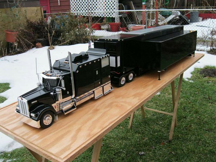 a toy truck is sitting on top of a wooden table in the yard with snow around it