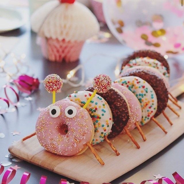 donuts with sprinkles and eyes are on a wooden board next to streamers