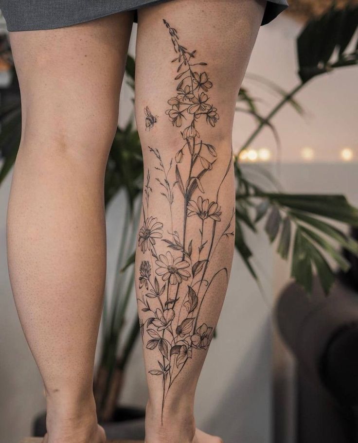 a woman's legs with flowers tattooed on the lower part of her leg and bottom half