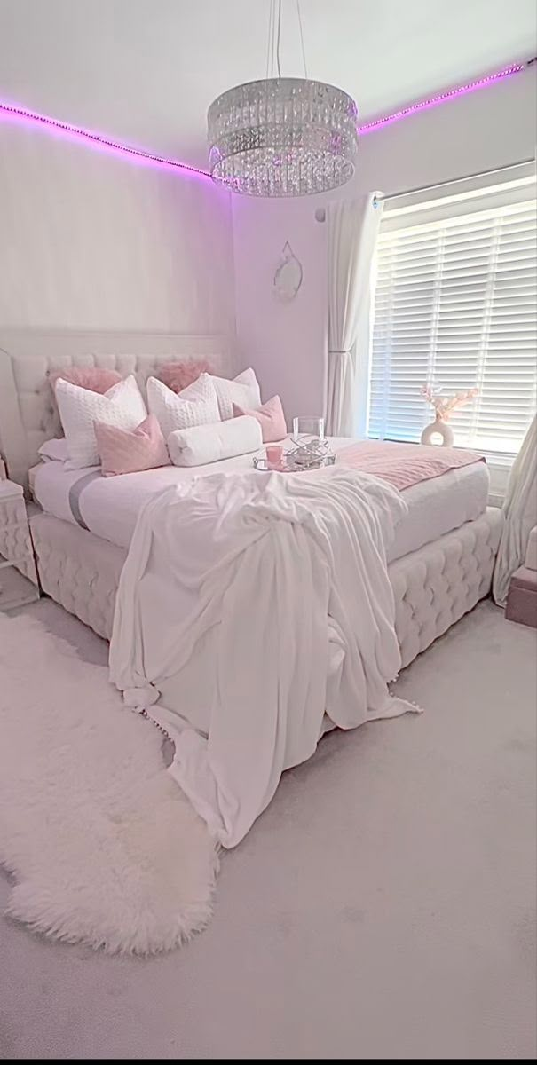 a bedroom with a bed, chandelier and white carpeted flooring in front of a window