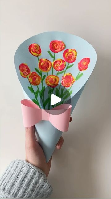 a person holding a paper bouquet with flowers on it