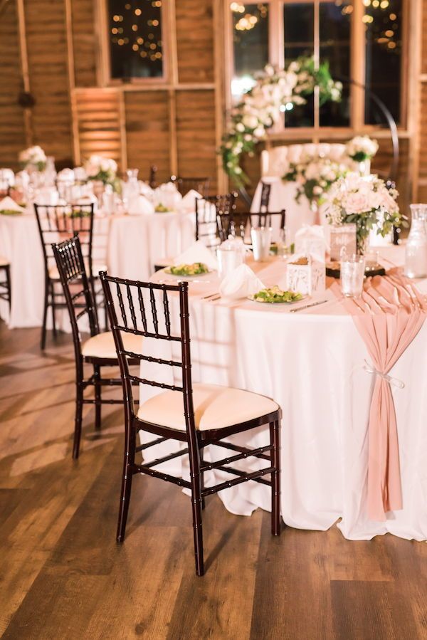 the table is set with white linens, pink sashers and floral centerpieces