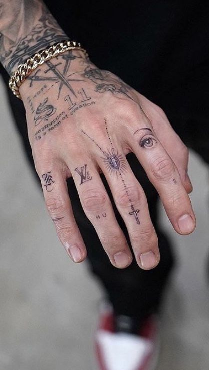 a man with tattoos on his hand and wrist is wearing a gold chain around his finger