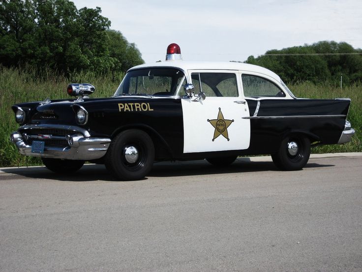 an old police car is parked on the side of the road