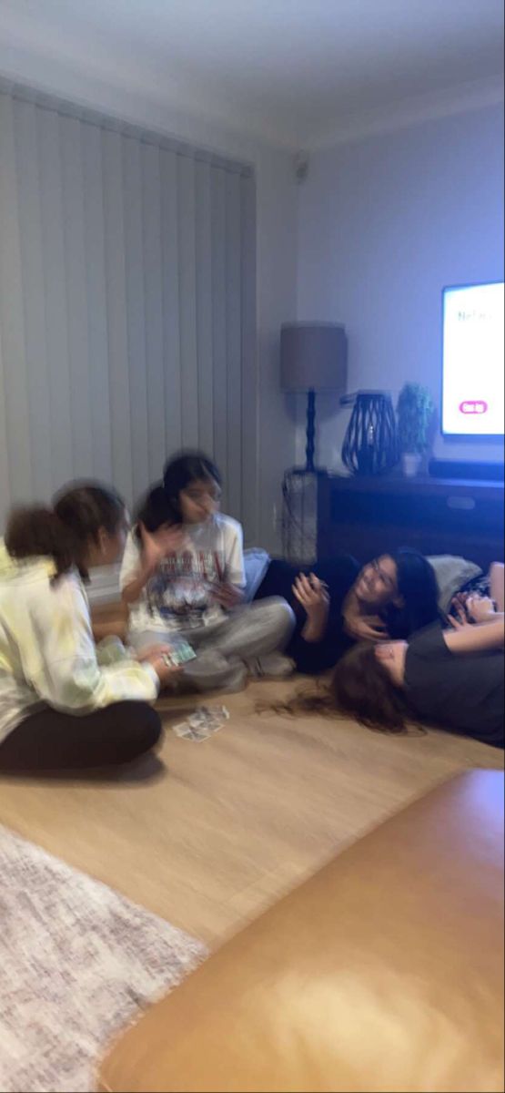 four people sitting on the floor in front of a flat screen tv