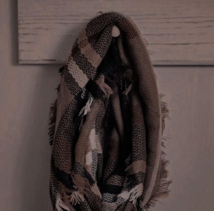 a plaid scarf hanging on a white wooden door with wood planks in the background