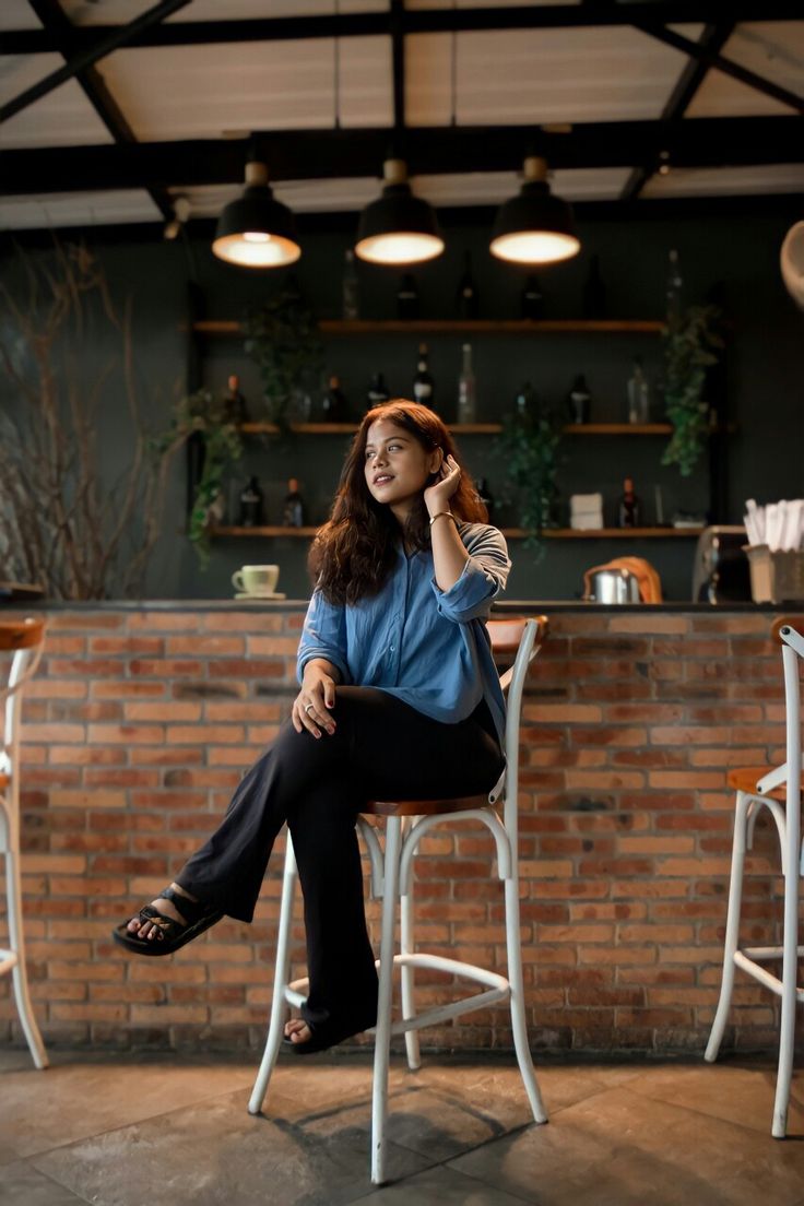 a woman sitting on top of a chair talking on a cell phone next to a brick wall