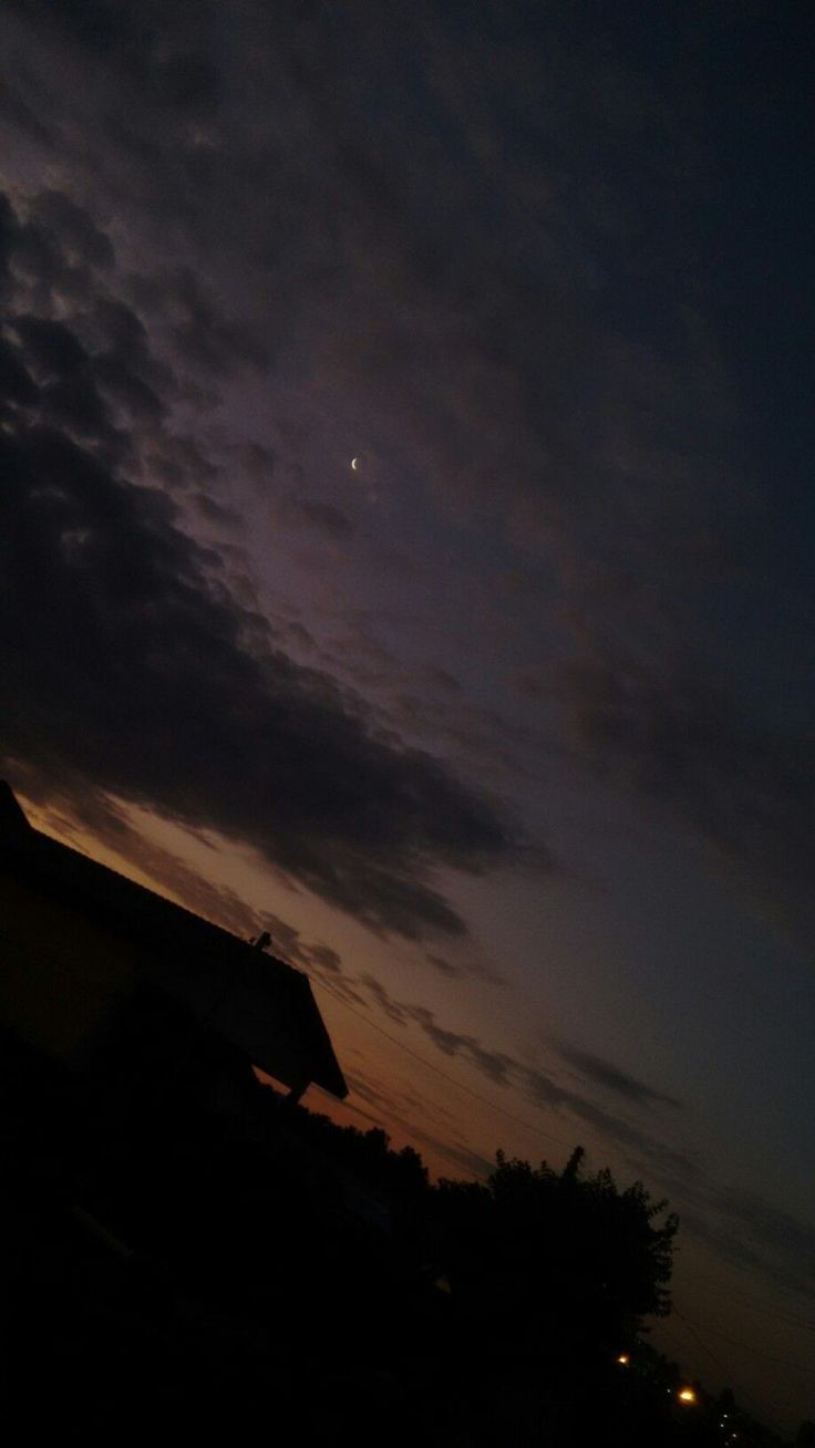 the sky is dark and cloudy at night, with some clouds in the background as the sun sets