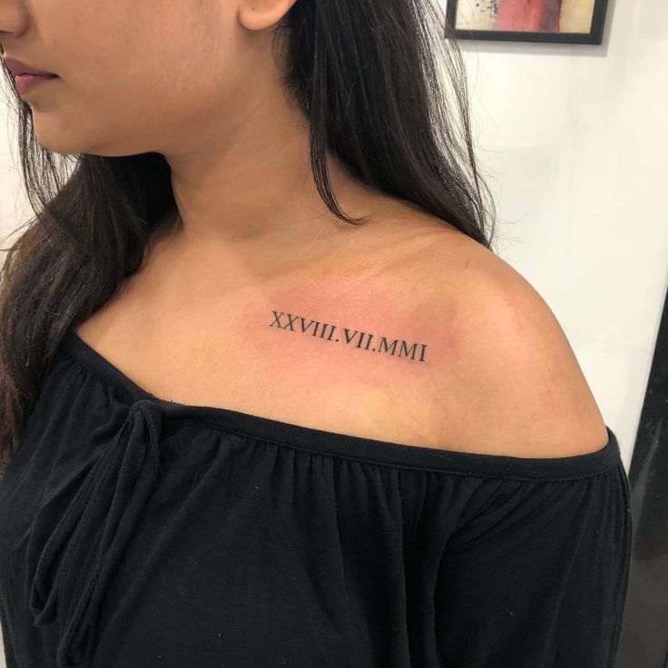 a woman's shoulder with roman numerals tattoo on her left upper arm