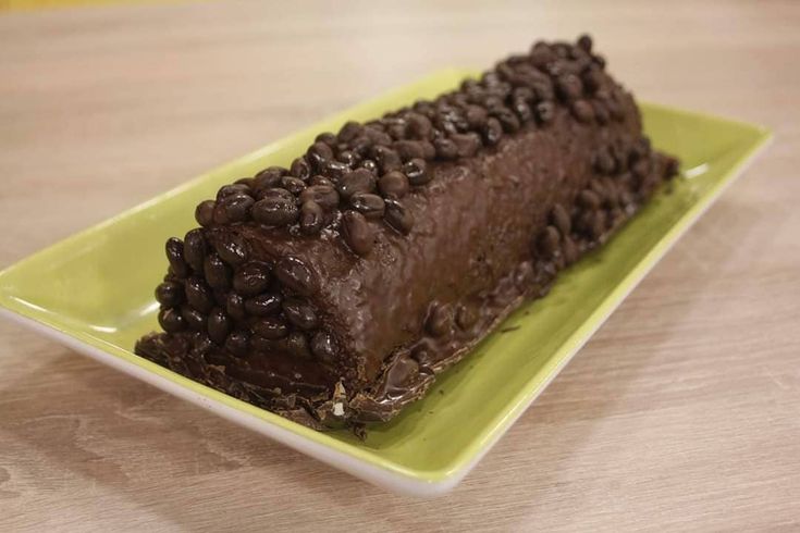 a piece of chocolate cake sitting on top of a green plate with coffee beans all over it