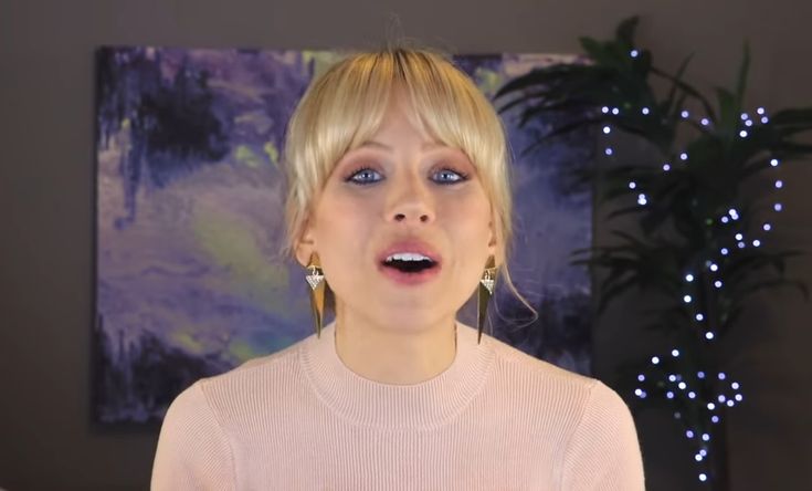 a woman with blonde hair and blue eyes is making a funny face while standing in front of a christmas tree