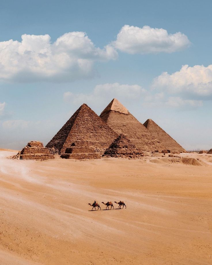 three pyramids in the desert with people riding horses