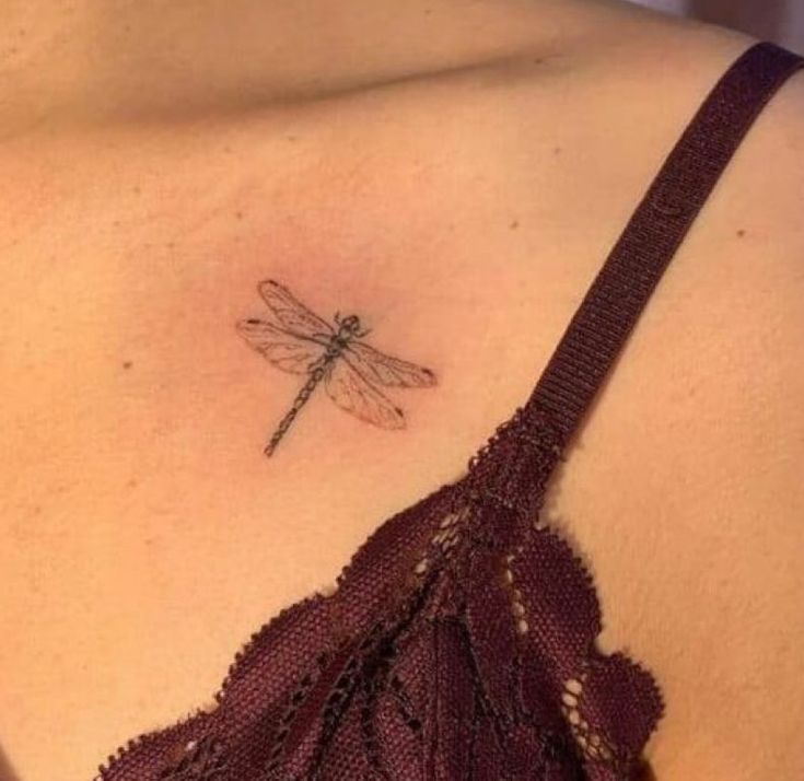 a woman's chest with a small tattoo of a dragonfly on the side