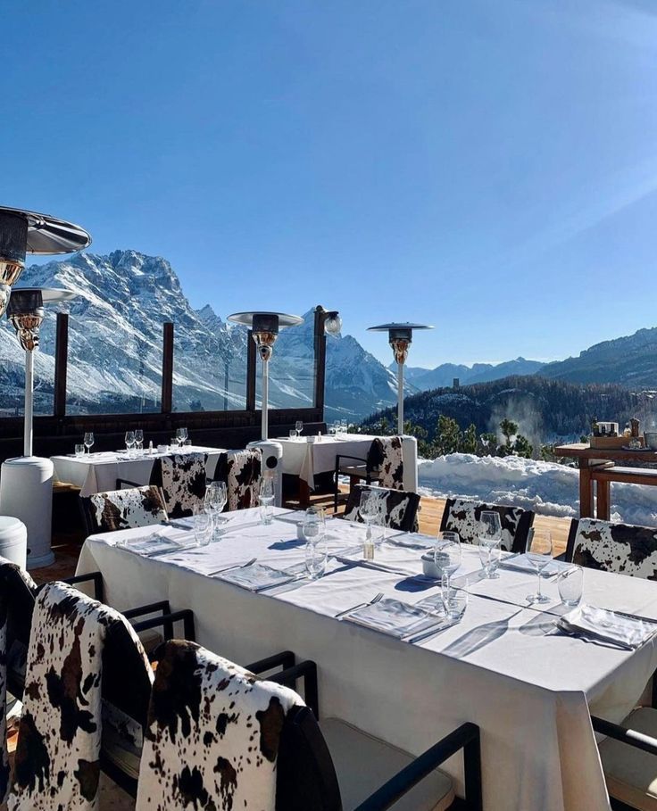 an outdoor dining area with white table cloths and black and white patterned chairs, overlooking the mountains