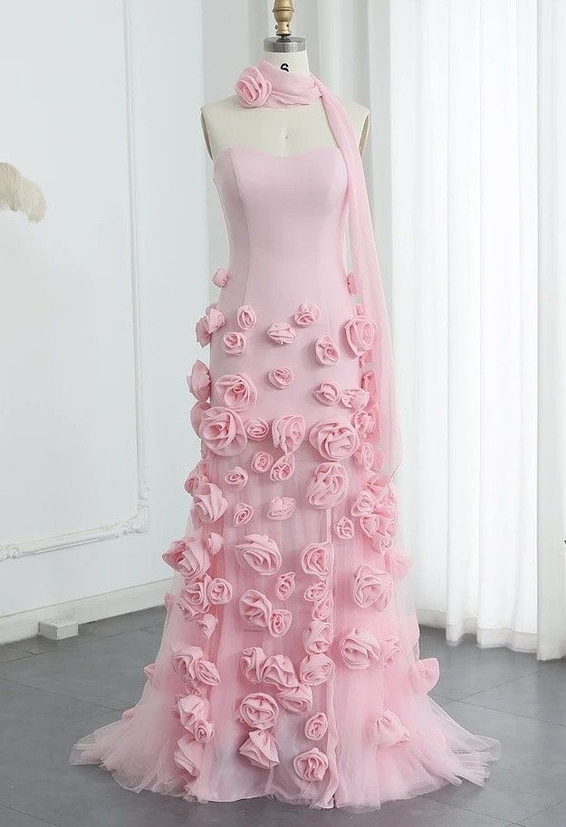 This gown is a striking shade of pink, featuring a strapless design with a sweetheart neckline that elegantly accentuates the collarbone and shoulders. The standout feature of the gown is the intricate 3D rose detailing, which adds a touch of romance and sophistication. The gown is complemented by a matching 3D rose neck choker, creating a cohesive and eye-catching look. This outfit is perfect for a formal event or a special occasion where you want to make a memorable impression.  Production tim 3d Flower Fashion, Trending Gown Designs, 3d Dress Design, Rose Inspired Outfits, Pink Christmas Dress, Pink Princess Gown, 3d Flower Dress, Pink Rose Dress, Flower Prom Dress