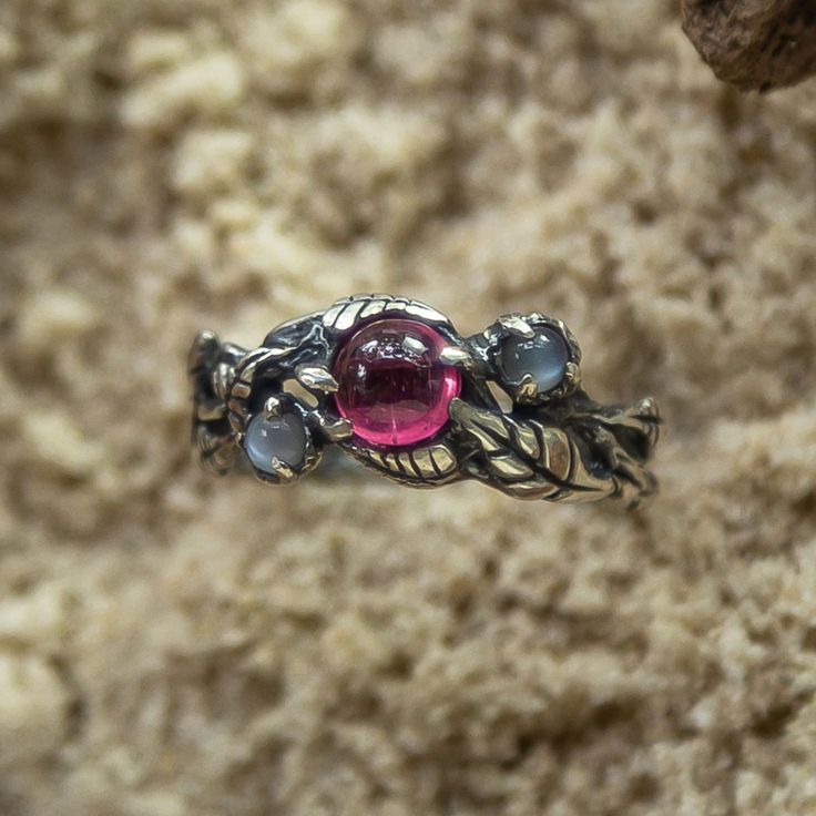 The "June" floral Pink Tourmaline engagement ring embodies the harmonious beauty of nature. Handcrafted with love and care, it showcases a radiant Pink Tourmaline at its heart, embraced by delicate floral motifs, symbolizing the blossoming of love and life. The "June" ring, with its antique allure, features an oxidized silver finish that exudes a sense of timeless wisdom. Adorned with two mystical Rainbow Moonstones, this three-gemstone ring channels celestial energy and spiritual balance. Embra Celestial Energy, Pink Tourmaline Engagement Ring, Spiritual Balance, Vintage Silver Ring, Rose Stone, Gothic Ring, Woman Ring, Vintage Silver Rings, Pink Tourmaline Ring