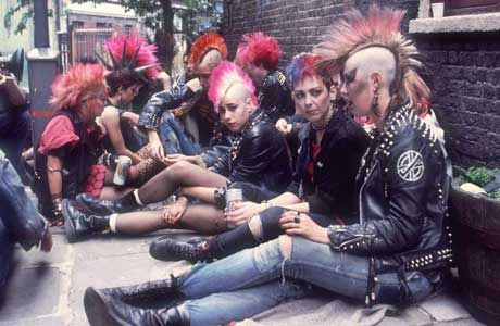 a group of people sitting next to each other on the ground in front of a brick building