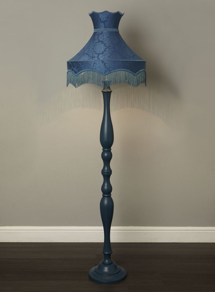 a blue lamp on a wooden floor next to a wall with a white and gray background