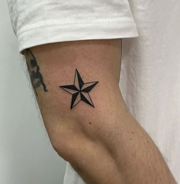 a black and white photo of a person's arm with a star tattoo on it