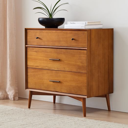 a wooden dresser with two drawers and a potted plant sitting on top of it