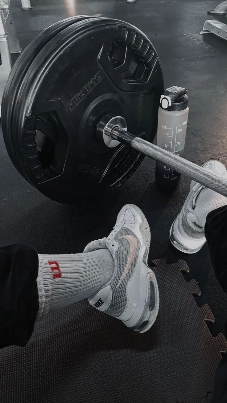 a person lifting a barbell in a gym with their feet up on the ground