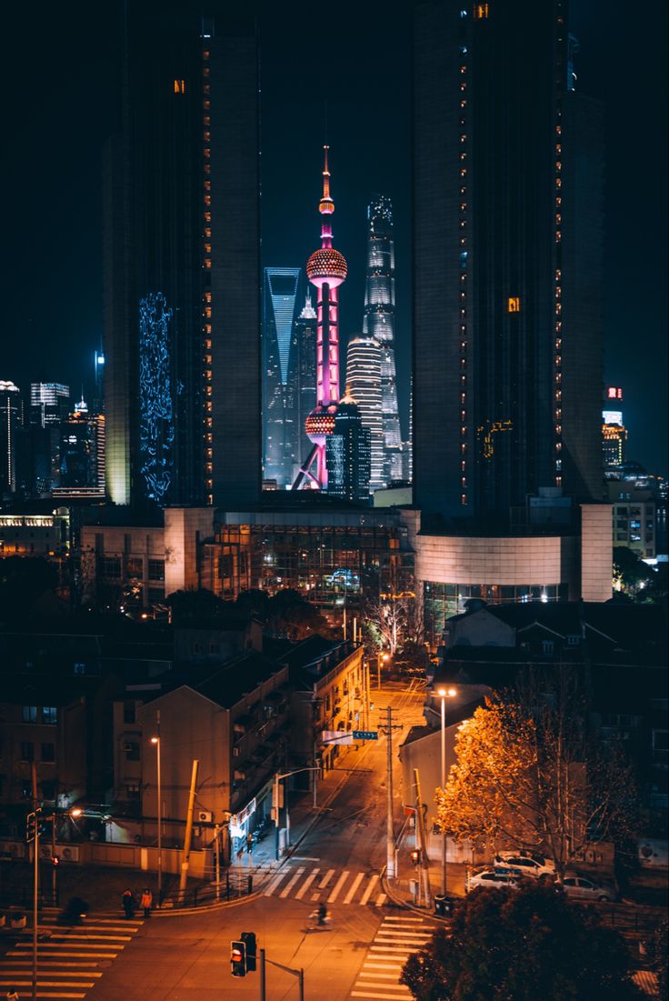 a city at night with tall buildings lit up in the distance and street lights on