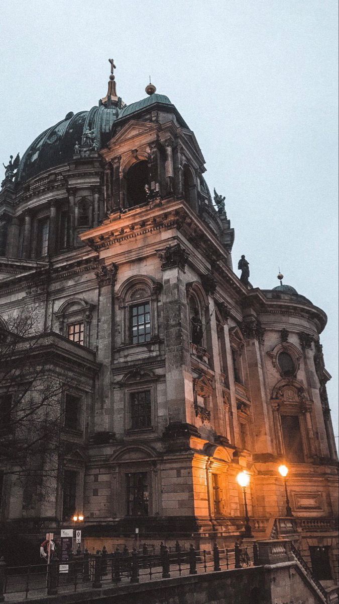 an old building lit up at night with street lights in the foreground and stairs leading to it