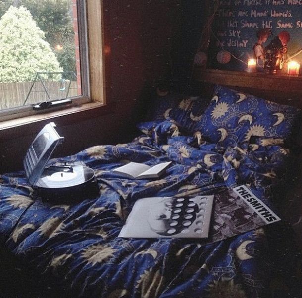 an unmade bed in front of a window with writing on it