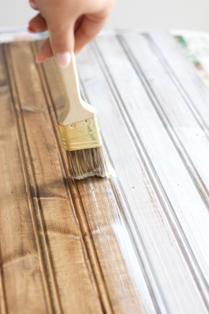 a person holding a paint brush on top of a wooden table