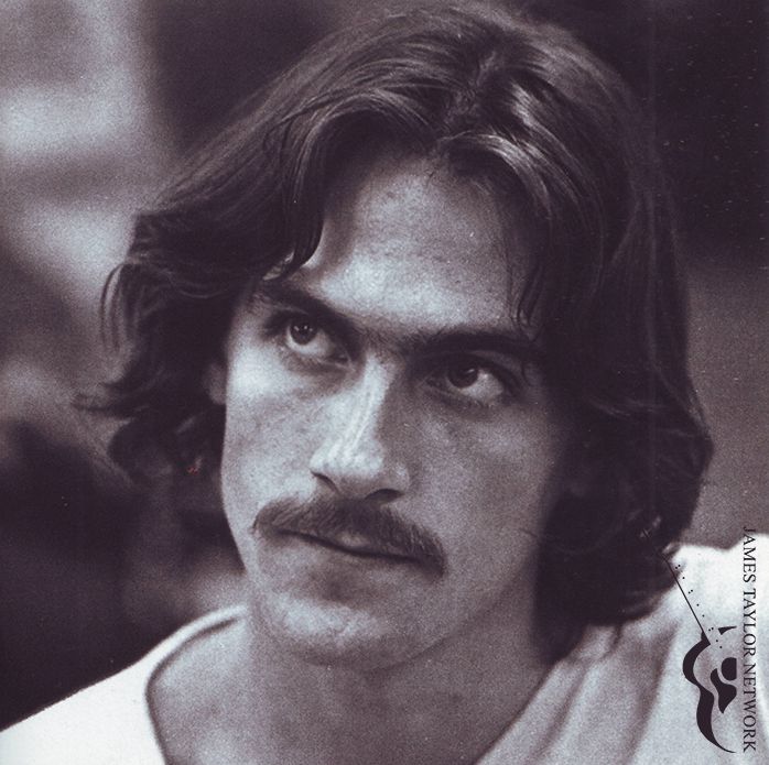 a man with long hair and a moustache on his face looking at the camera