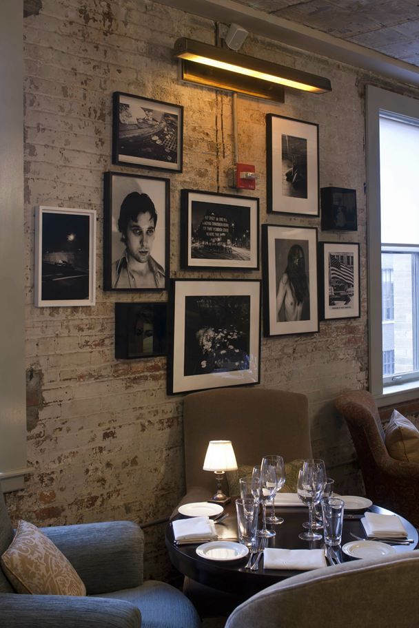 a restaurant with pictures on the wall and chairs in front of it, along with wine glasses