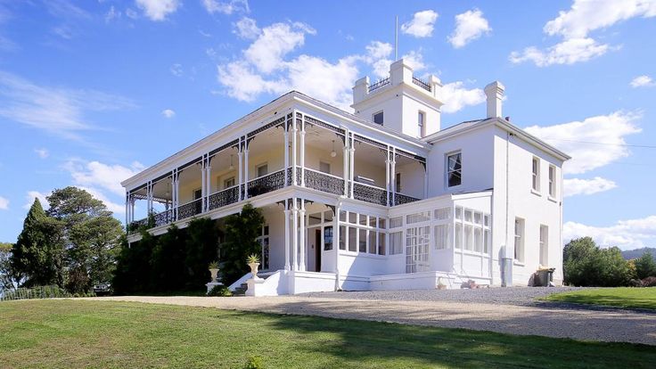 a large white house sitting on top of a lush green field