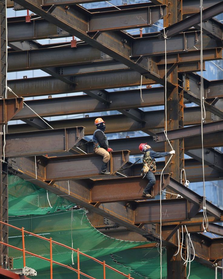 two men working on the side of a large metal structure with scaffolding around them