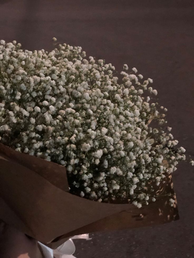 a bouquet of white flowers sitting on top of a brown paper bag