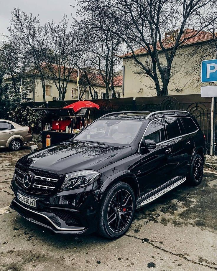 a black mercedes gls parked in front of a parking meter